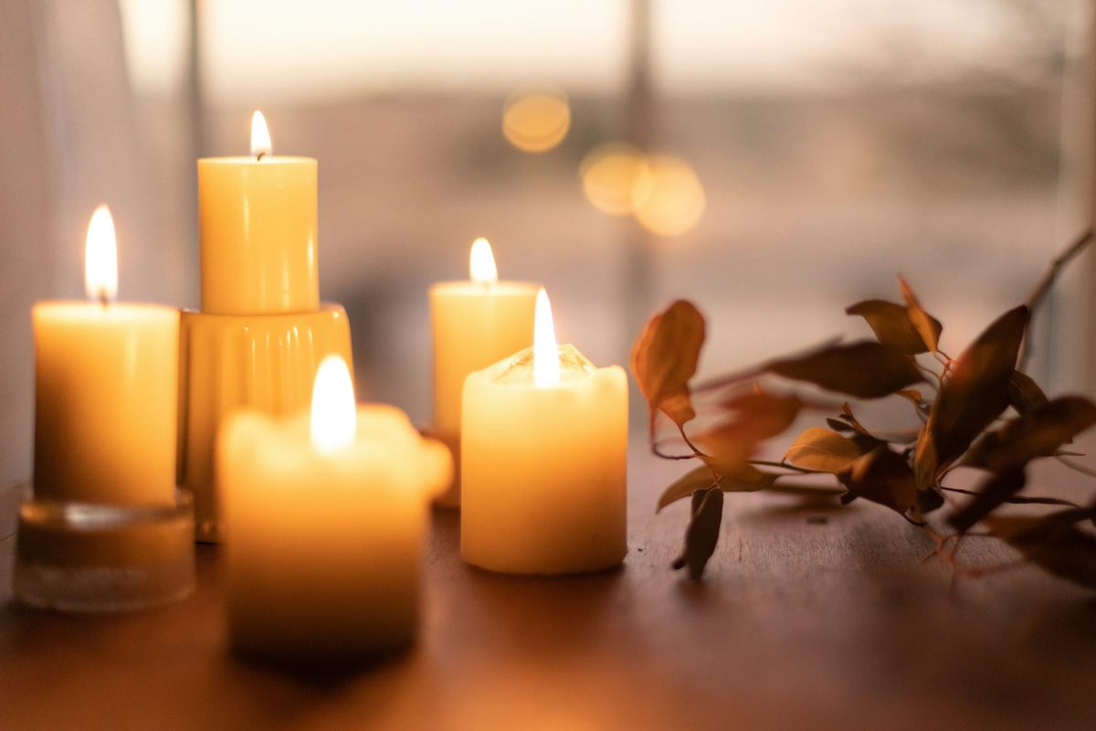 Velas pilar encendidas, de cuerpo ancho y mecha fina asomando arriba: la proporción cuerpo-mecha que da origen al nombre y a la anatomía de una vela japonesa en un candlestick chart